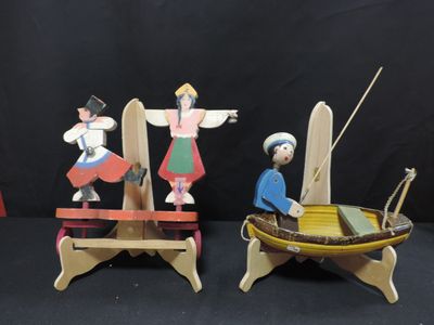 two wooden figurines of people in a boat and a man in a boat