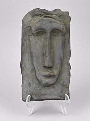 sculpture représentant le visage d'un homme, posée sur un socle, sur fond blanc