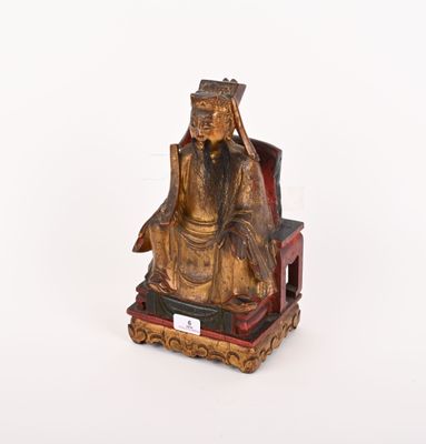 une statue en or représentant un homme assis sur une chaise