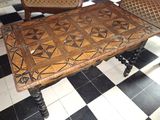 une table avec un plateau en bois posée sur un sol à damier noir et blanc