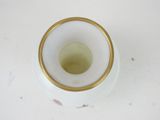 a white vase with a gold rim sitting on a table