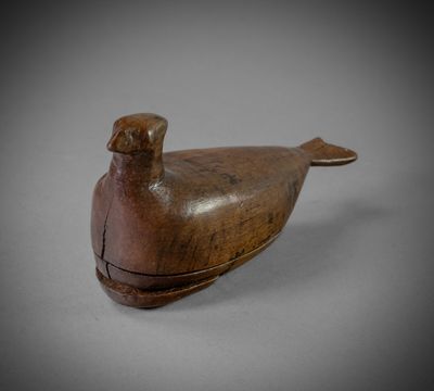 an old wooden bird sitting on top of a white surface