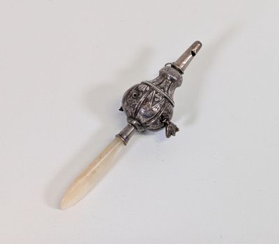 une cuillère en argent avec un manche en bois posée sur une surface blanche