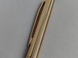 a gold pen sitting on top of a white surface