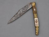 an old knife with a gold handle on a gray surface