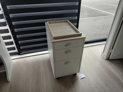 a white cabinet with drawers in front of a window