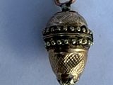 a small gold bell hanging from a chain on a white surface