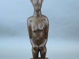 un gros plan sur une statue en bois représentant une femme, posée sur un socle