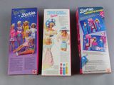 two boxes of barbie dolls sitting on top of a table