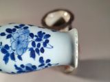 a blue and white vase sitting on a table next to a coin