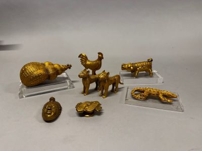 plusieurs figurines en or représentant des animaux et des oiseaux, posées sur des socles en acrylique transparent
