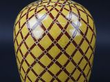 un vase en forme de pomme orné d'un motif rouge et jaune