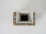 a small square vase with a flower design on it