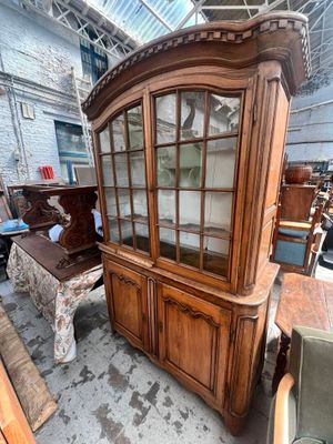 un vaisselier en bois avec des portes vitrées, placé au milieu d'une pièce
