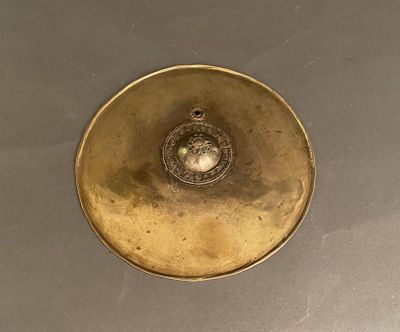 une assiette en or posée sur une table, sur fond noir