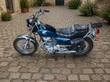 une moto bleue garée dans une rue pavée