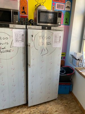 two refrigerators that are covered with stickers in a kitchen