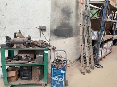 une étagère verte sur laquelle sont posés des outils, à côté d'une échelle