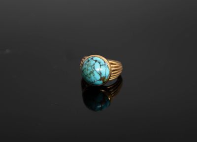 une bague en or sertie d'une turquoise sur un fond noir