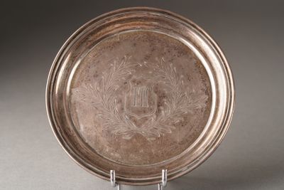an antique silver plate with a design on it on a stand