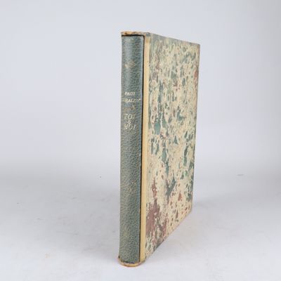 un vieux livre posé sur une table blanche à côté d'un mur blanc