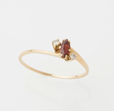 a gold ring with a red stone and two white diamonds