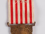 an old medal with a red and white ribbon on a white surface