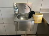 un lavabo dans des toilettes publiques, avec un seau posé par terre