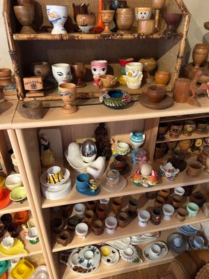 une étagère en bois sur laquelle sont disposées de nombreuses pièces de poterie de styles variés
