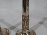 deux bougeoirs en argent posés sur une table blanche