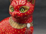 red cat figurine with yellow spots and green eyes sitting on a black surface
