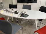 une table blanche entourée de chaises, avec une télévision accrochée au mur