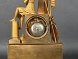 a gold clock with a statue sitting on top of it