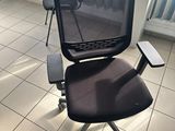 a black office chair sitting in a room with a blue wall