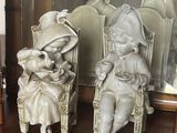 deux figurines représentant des enfants assis sur une chaise devant un miroir