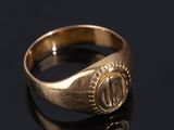 a close up of a gold signet ring on a black surface