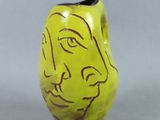 un vase jaune sur lequel est peint un visage