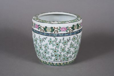 un vase blanc orné de motifs verts et roses