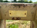un banc en métal rouillé sur lequel est accrochée une pancarte