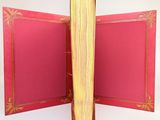an open book with a red cover sitting on top of a table