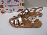 silver and gold sandals on a white surface with a box in the background