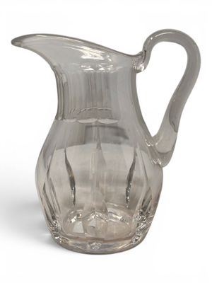 clear glass pitcher on a white surface with a white background