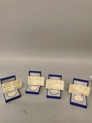 four different types of silver coins in boxes on a table