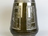 a black vase with a cross on it sitting on a table