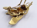 a gold plated brooch with a pair of shoes and a pair of golf clubs