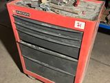 une boîte à outils rouge posée dans un garage, avec des outils dessus