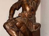 a bronze statue of a man sitting on a bench