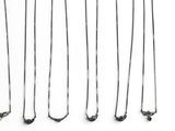 many different types of silver necklaces on a white surface