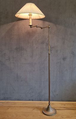 une lampe posée sur un parquet, devant un mur gris