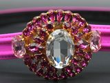 a close up of a pink bracelet with an oval crystal center
